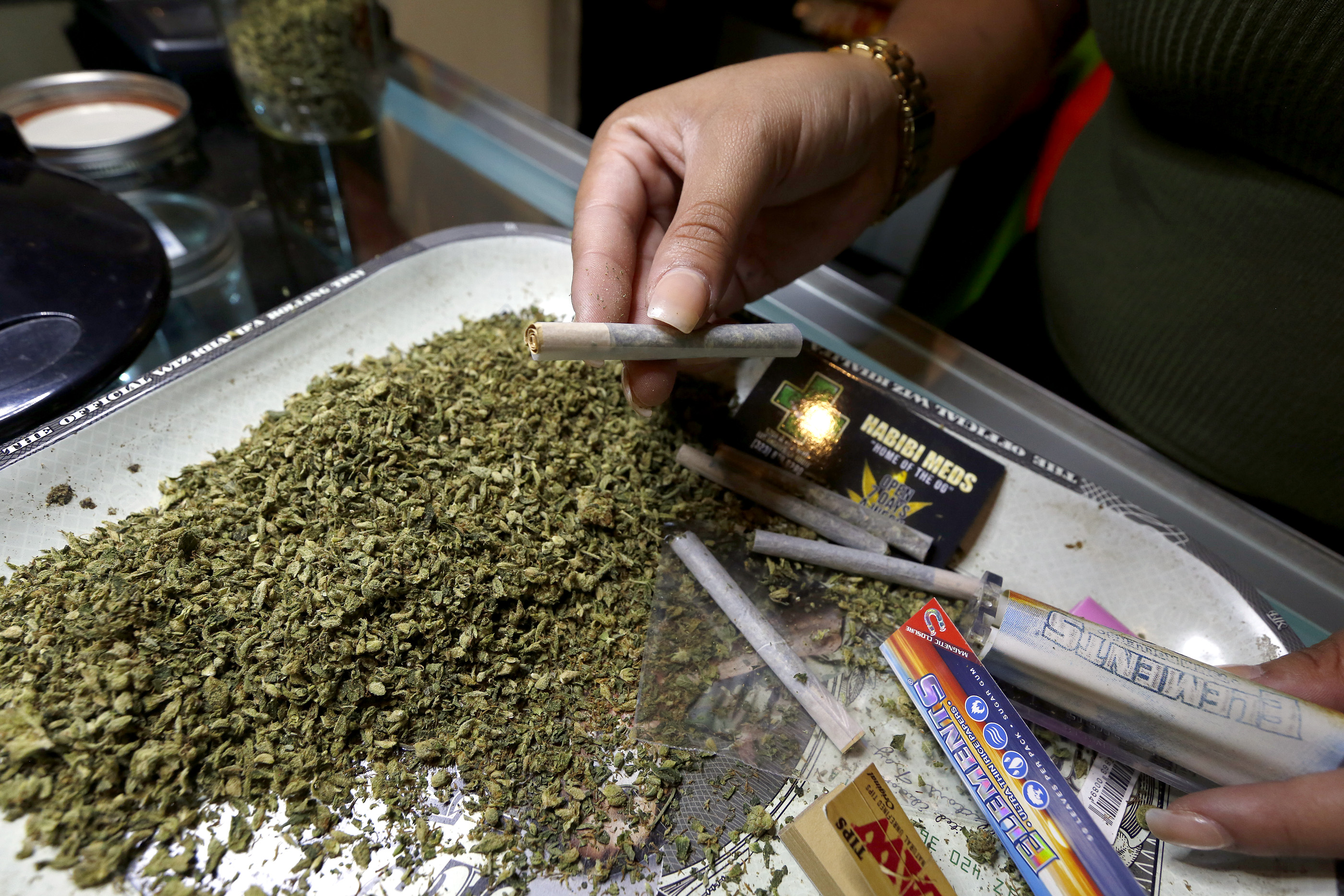 Una empleada de un negocio de marihuana enrolla un cigarro de la hierba. (Aurelia Ventura/ La Opinion)