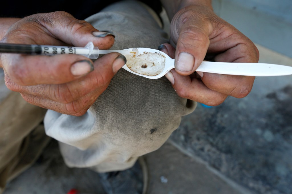 10/01/15 /TIJUANA/Juan Luis Perez, 32, deported from Hawaiian Gardens and drug user prepares a mixture of heroin and water next to a border crossing stations that leads from Tijuana, Mexico, into the United States. (Photo by Aurelia Ventura/La Opinion)