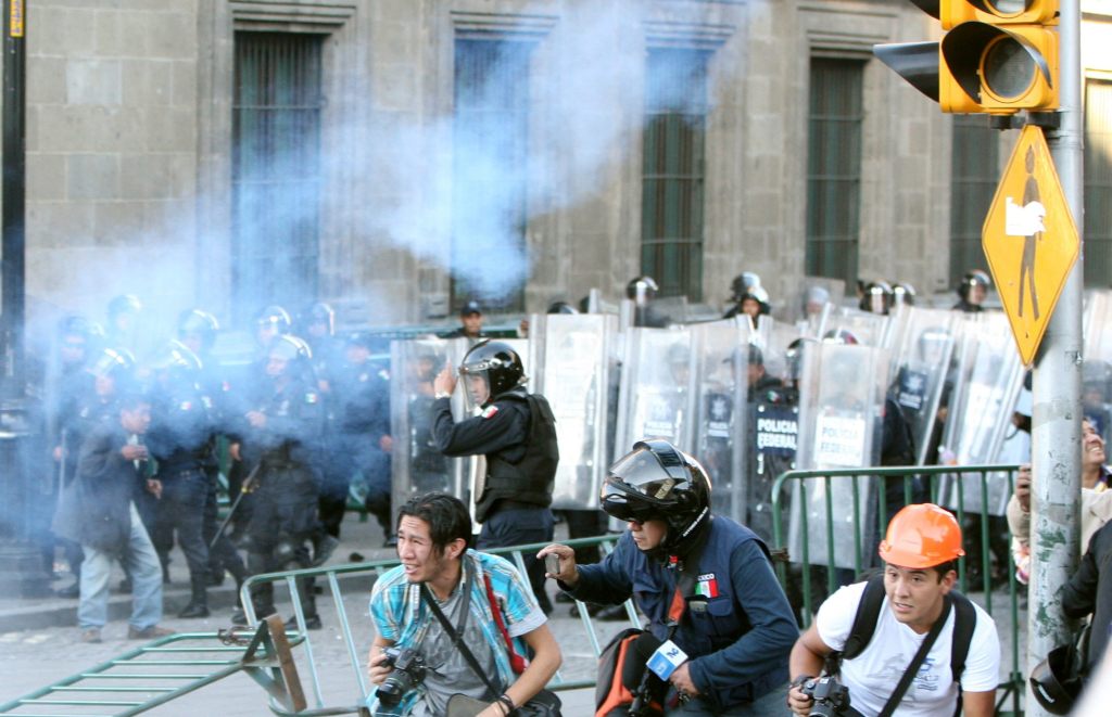 Un grupo de encapuchados se enfrentan con la Policía en el Zócalo de Ciudad de México, durante la marcha por el aniversario de la matanza de Tlatelolco.