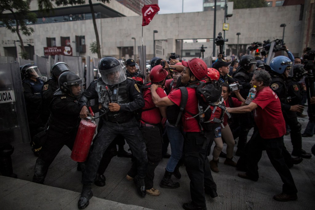 Manifestantes chocan con la policía antidisturbios tras una manifestación para pedir continuar con la búsqueda de los 43 estudiantes secuestrados el 26 de septiembre de 2014.