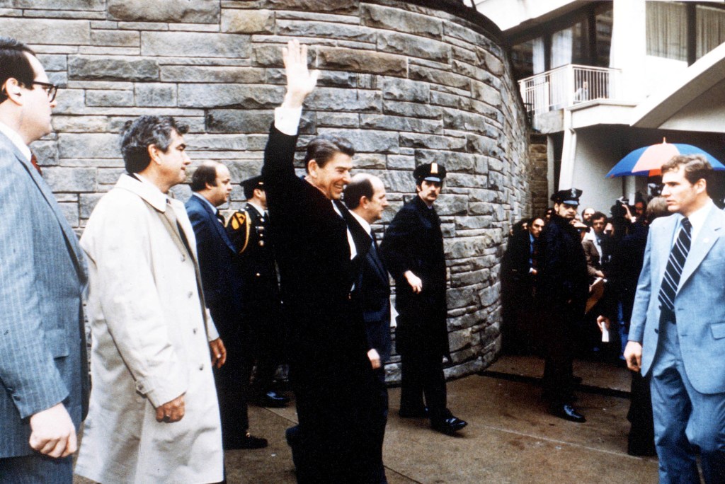 El presidente Reagan saluda a los presentes minutos antes del atentado el 30 de marzo de 1981. El secretario de prensa James Brady es el tercero desde la izquierda. 