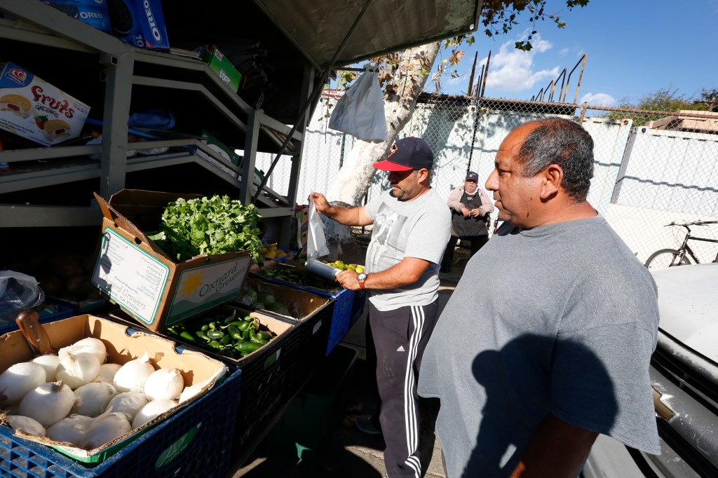 Ismael Herrera, operador de la camioneta, ayuda al residente René Soto a suplirse de frutas y verduras. /AURELIA VENTURA