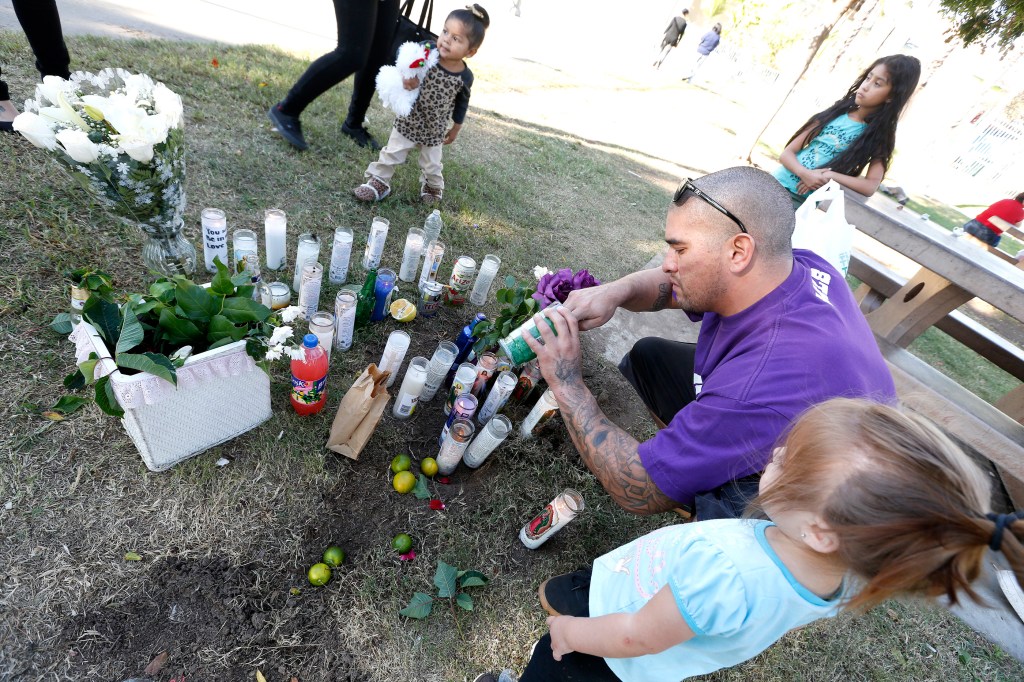 11/23/15 /LOS ANGELES/Antonio Navarro, with daughter Leilani, lights a candle in front of a make-shift memorial, next to the basketball courts of the Ruben F. Salazar Park in East Los Angeles, where Juan "Johnny" Aguilar, 28, and Antonio "Tony" Aguilar, 32 were fatally shot while playing basketball. Both men were parentsÊwith children under the age of 5, according to family friends. The two adult brothers were fatally shot Sunday morning while playing basketball at a park in theÊEast Los Angeles area. The shooting took place about 11 a.m. at Ruben F. Salazar Park, in the 3860 block of Whittier Boulevard, according to a statement from the Los Angeles County SheriffÕs Department. (Photo by Aurelia Ventura/La Opinion)