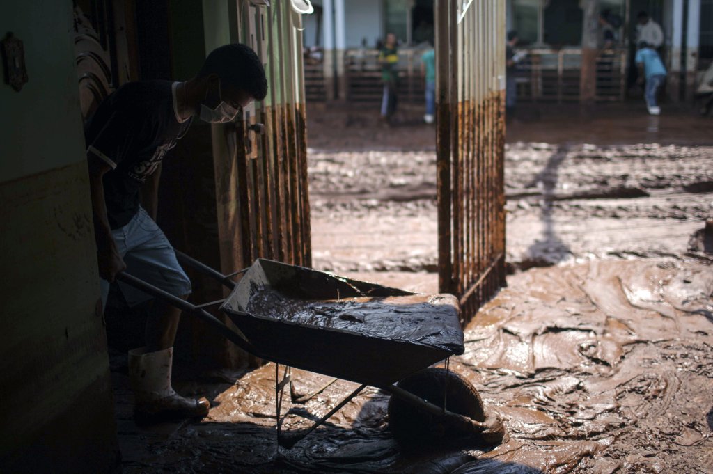 Un hombre intenta limpiar su casa anegada por el lodo de una mina de la empresa Samarco, en Mariana, Minas Gerais.