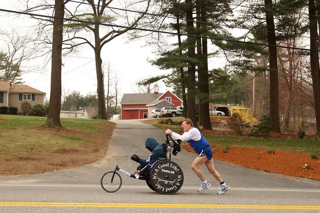 HOPKINTON, MA - APRIL 21: Dick Hoyt pushes Rick Hoyt as they compete in the 2008 Boston Marathon on April 21,2008 in Hopkinton, Massachusetts. Nearly 25,000 people participated in the race. (Photo by Elsa/Getty Images)
