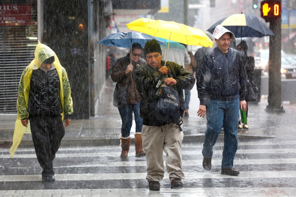 Personas intentan protegerse de la fuerte lluvia en el centro de Los Ángeles. / AURELIA VENTURA