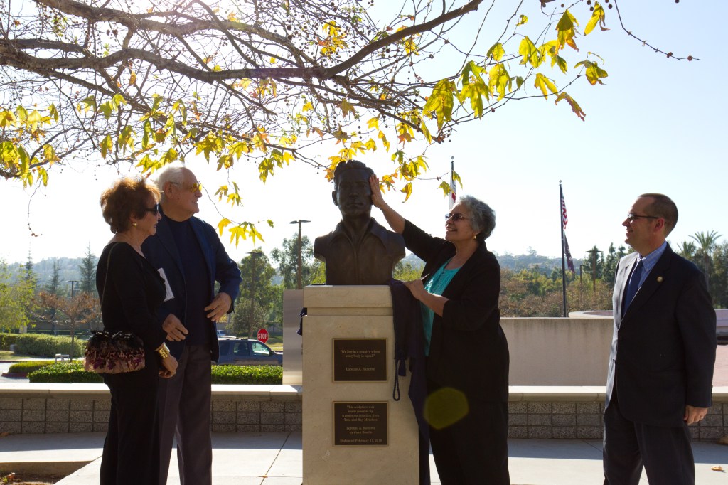 Phyllis Ramírez toca el busto conmemorativo de su padre, Lorenzo Ramírez, develado en Orange, California.
