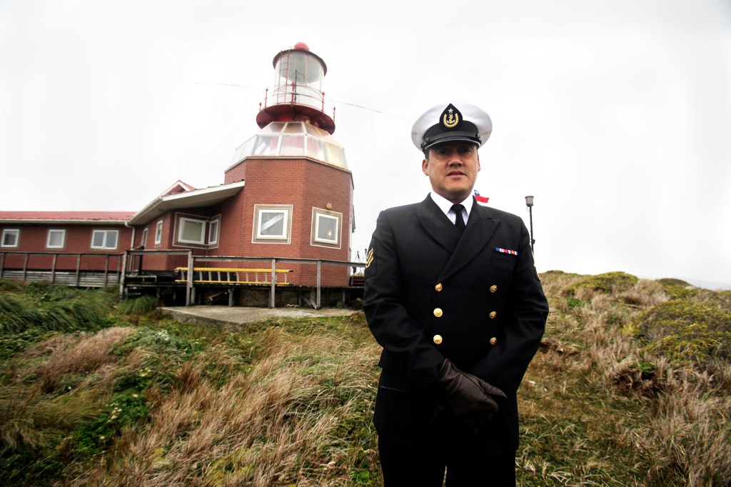 El sargento de la Armada de Chile José Aguayo posando junto al faro ubicado en la Isla de Cabo de Hornos.