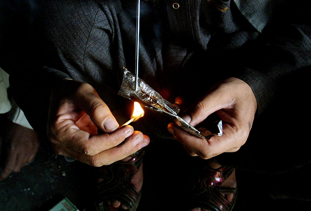 Un adicto a la heroína quema la droga antes de inhalarla. Foto: Getty