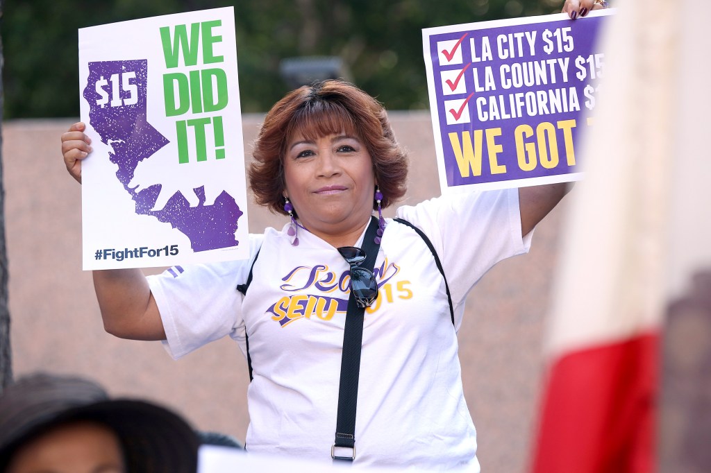 Empleados celebran después que el gobernador de California Jerry Brown firma en ley el incremento del salario mínimo a 15 dólares por hora, durante una ceremonia en el centro de Los Ángeles. La propuesta de aumentar el salario mínimo en California a $15 por hora para el año 2022 fue aprobada ayer por la legislatura estatal. (Foto: Aurelia Ventura/La Opinion)