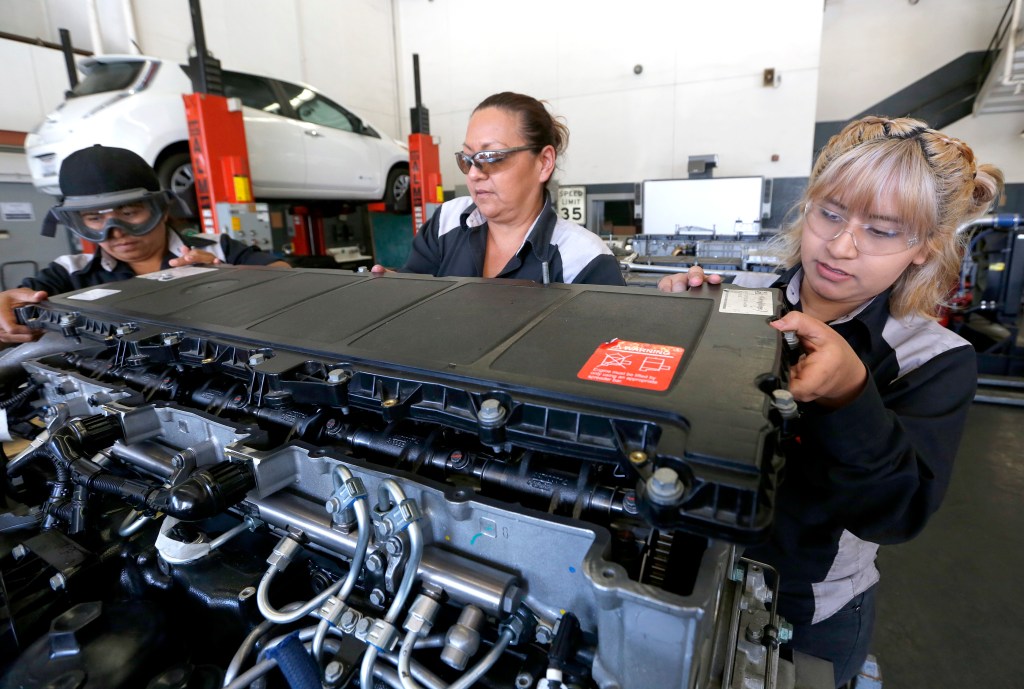 Armi Sandoval, Lisa Delgado y Amy Francisco trabajan en un motor. (Aurelia Ventura/ La Opinion)