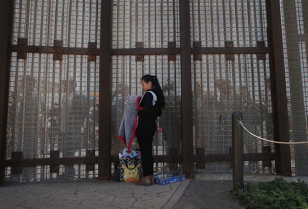 Karen Herrera, de 23 años, sostiene a su bebé , mientras habla con miembros de la familia a través de la valla de la frontera EEUU-México el 30 de abril de 2016 en San Diego, California.