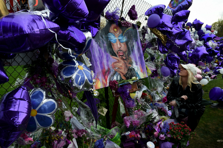 Un manto de flores, globos y recuerdos de color morado cubren los muros que rodean su casa de Paisley Park.