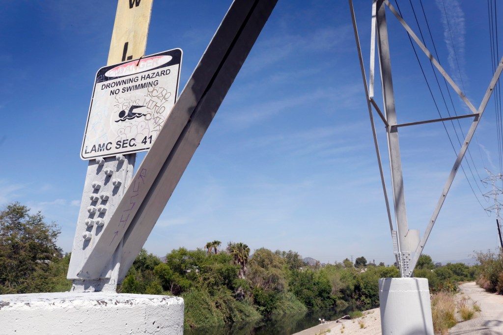 Un cartel antes de llegar al lugar donde fallecieron los jóvenes adiverte sobre el peligro de meterse al cauce y tratar de nadar. (Photo Aurelia Ventura/ La Opinion)