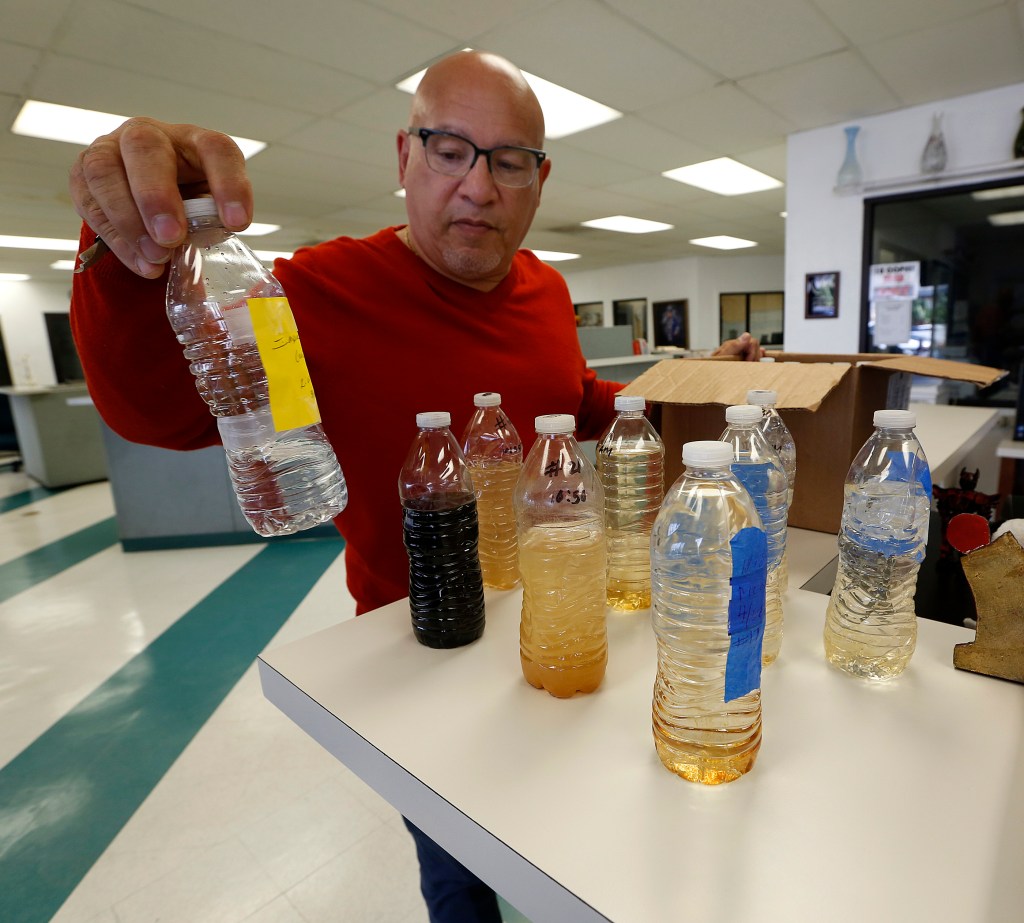 Timothy Watkins de la organización Better Watts Initiative muestra botellas con agua de diferente color que sale de las llaves en esta zona de Los Ángeles. (Aurelia Ventura/La Opinion)