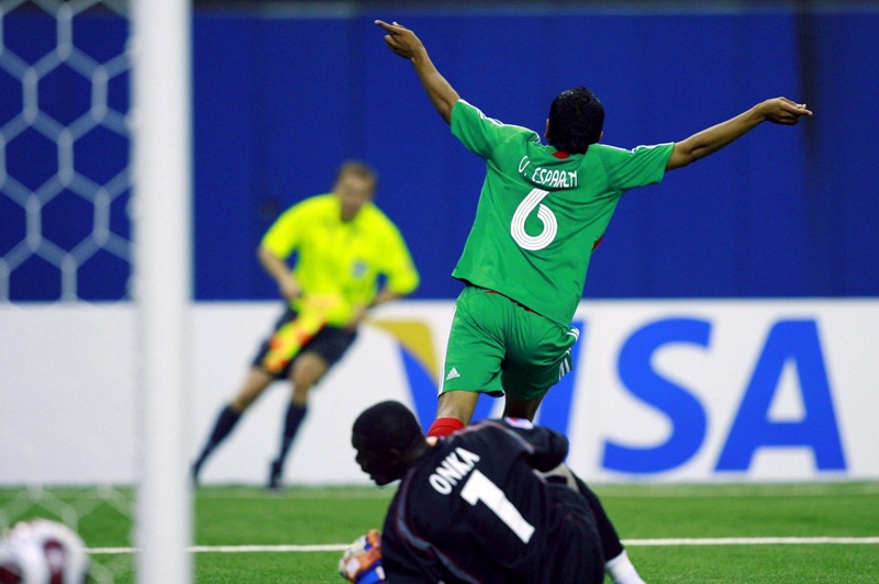 Omar Esparza de la selección mexicana Sub 20 festeja un gol al Congo mientras el portero Destin Onka yace en el pasto. La foto es del Mundial Sub20 de 2007 realizado en Canadá.
