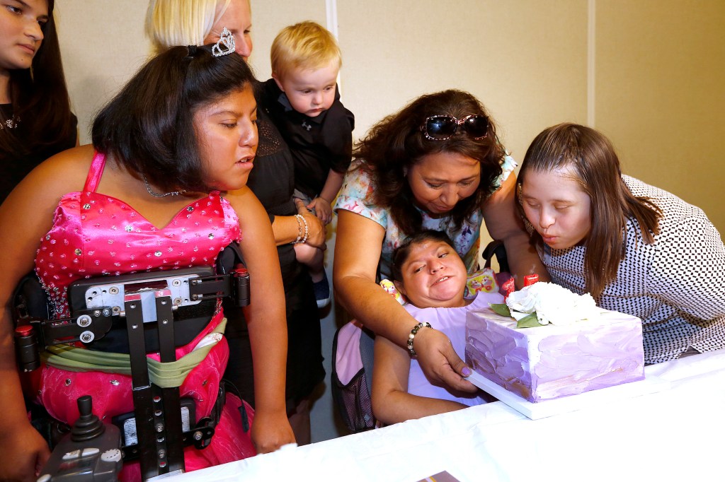 Florie Cajas ayuda a su hija adoptiva Teresa a apagar las velas del pastel de cumpleaños durante la celebración en el Children's Hospital Los Angeles. (Aurelia Ventura/ La Opinion)