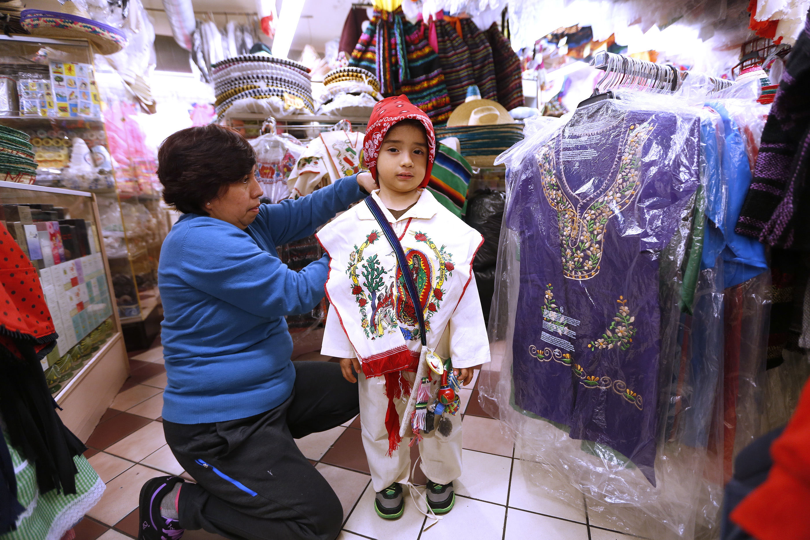 12/09/16 /LOS ANGELES/5 year-old Joshua Jimenez with his grandmother Mary Teresa Jimenez, from Thousand Oaks, tries on an outfit while shopping at the popular Mercadito in East Los Angeles. Hundreds of religious Catholics will be celebrating the Virgin of Guadalupe. (Photo by Aurelia Ventura/La Opinion)
