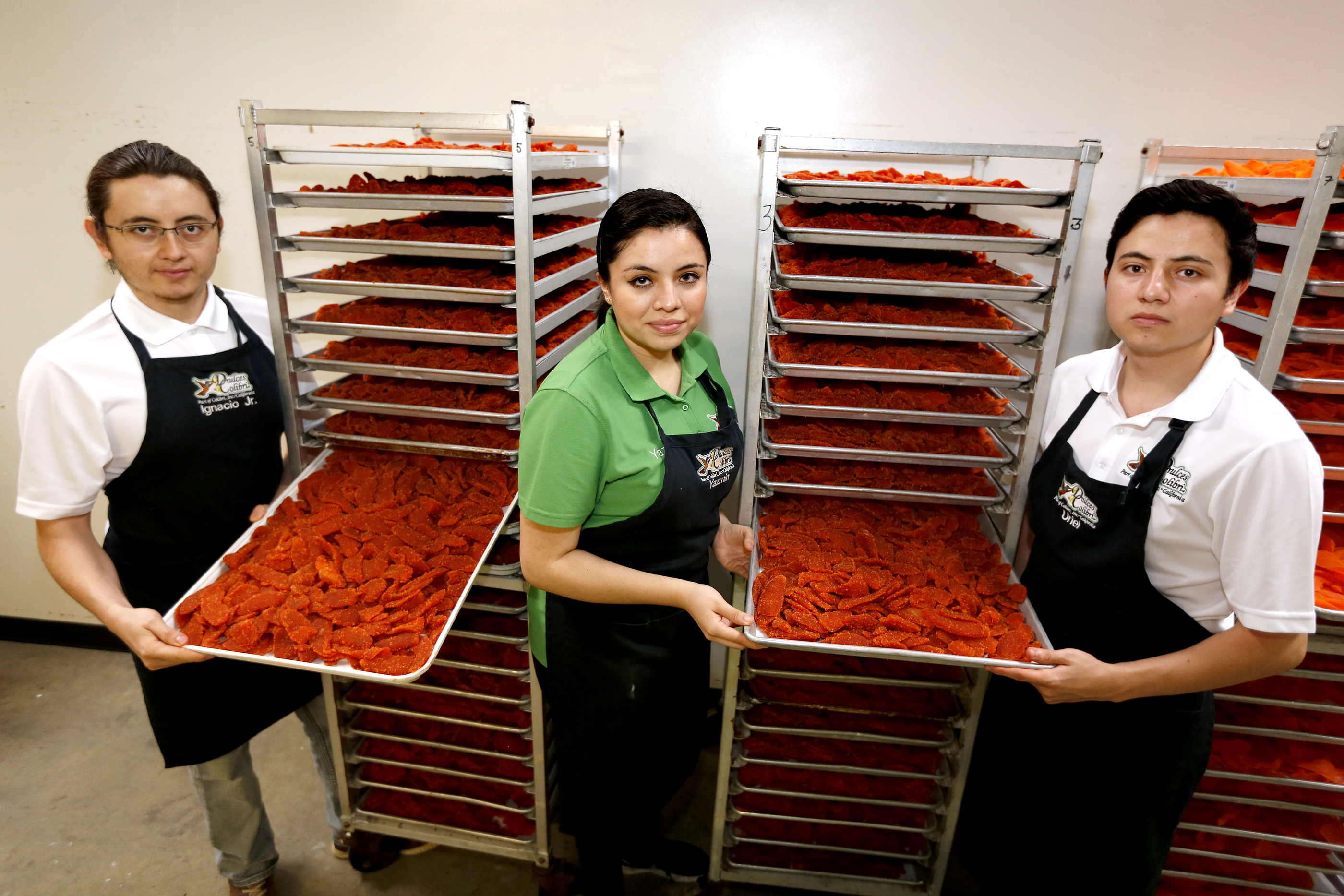 02/08/17/ LOS ANGELES/ Entrepreneur immigrant family Ignacio Jr. Viramontes, 29, with his siblings Yazmin, 23, and Uriel, 21, pose for a photograph next to their product, mango slices coated with chili, at their factory in Gardena. (Photo Aurelia Ventura/ La Opinion)