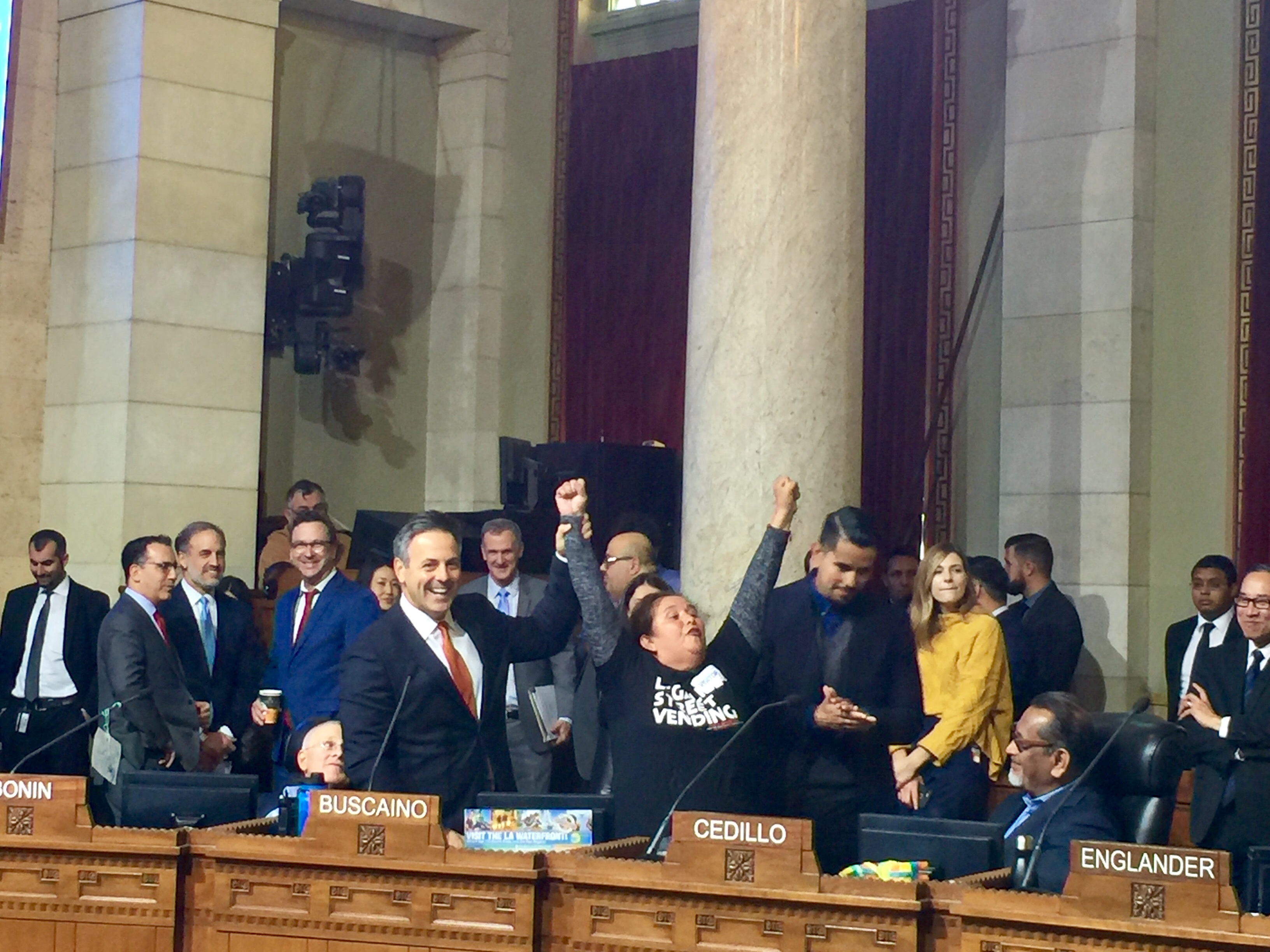 El concejal José Buscaíno celebra con una vendedora ambulante la aprobación de los permisos para que puedan trabajar en las aceras y parques de Los Ángeles. (Araceli Martínez/La Opinión).