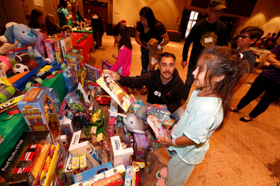 Sherlyn Cázares, de 8 años, y su padre, Victor, escogen entre decenas de regalos durante el evento . (Aurelia Ventura/La Opinion)