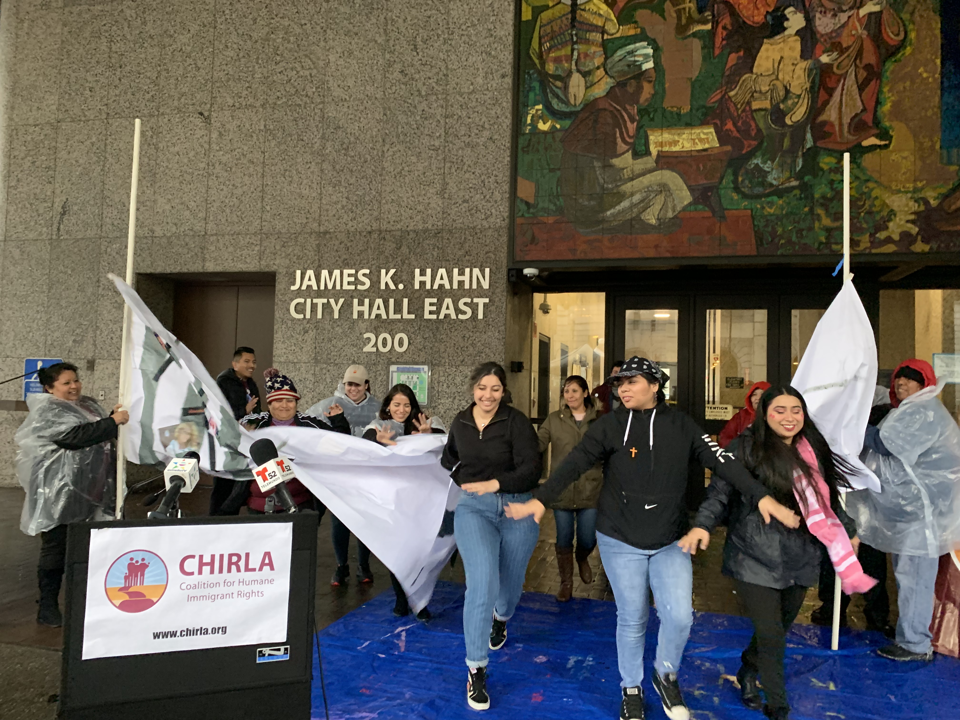 Miembros de CHIRLA rompieron una pancarta que simbolizaba el muro en la frontera. (Araceli Martínez/La Opinión).