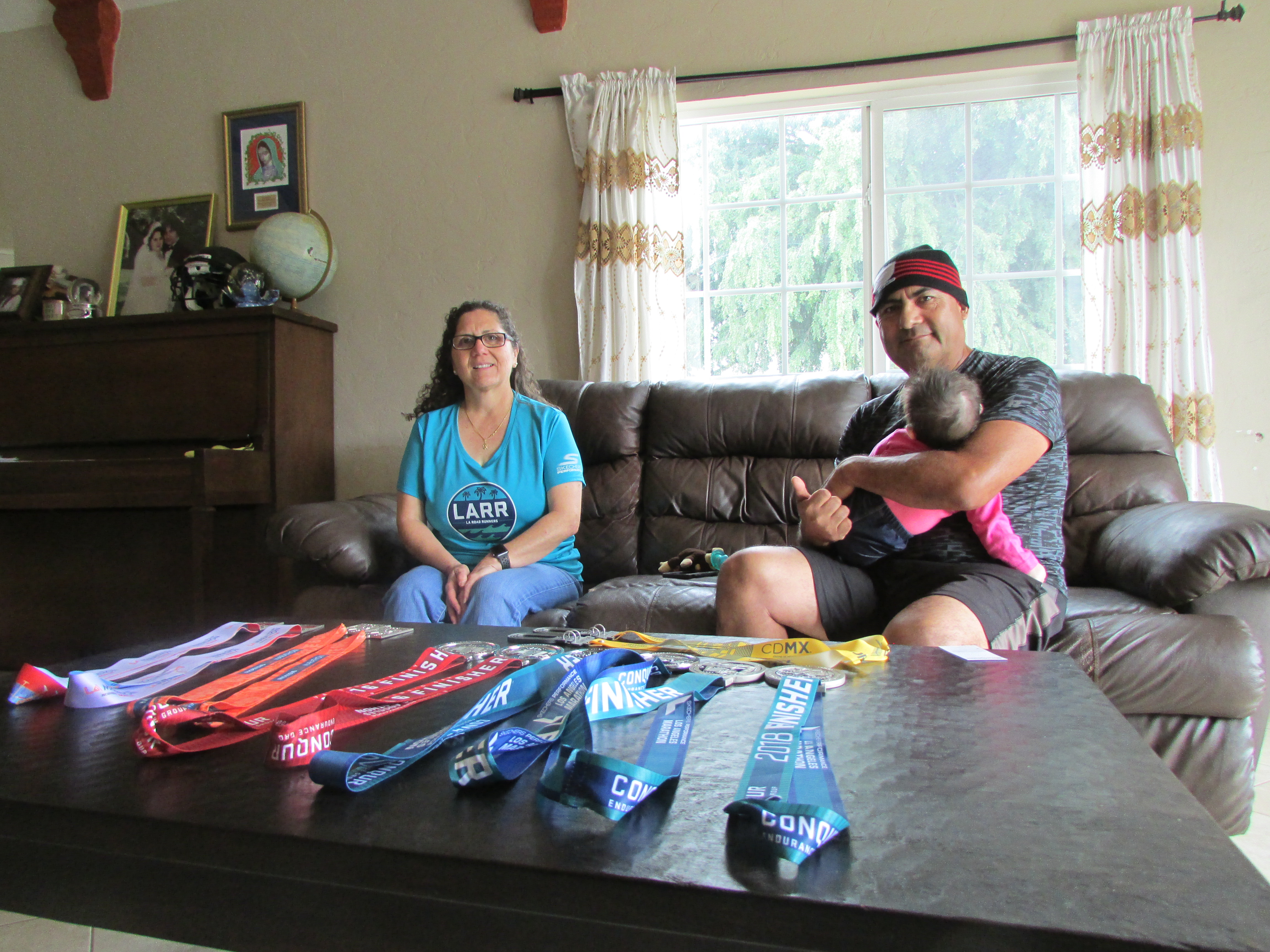 José Luis y Guadalupe Cadena muestras todas las medallas que han ganado en los maratones en los que han participado en Los Ángeles y la ciudad de México. (Araceli Martínez/La Opinión).