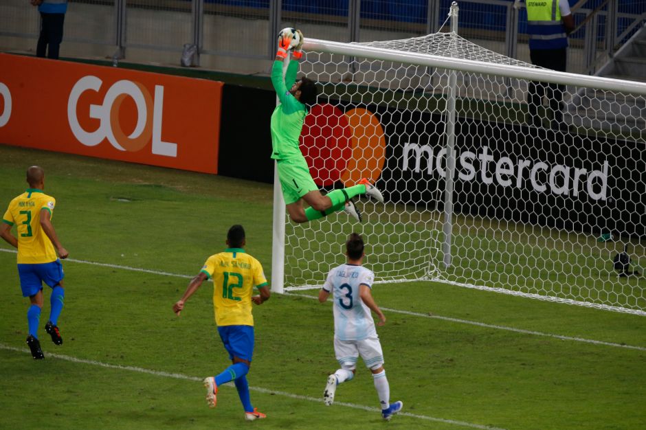 Alisson atajando tire libre de Messi.